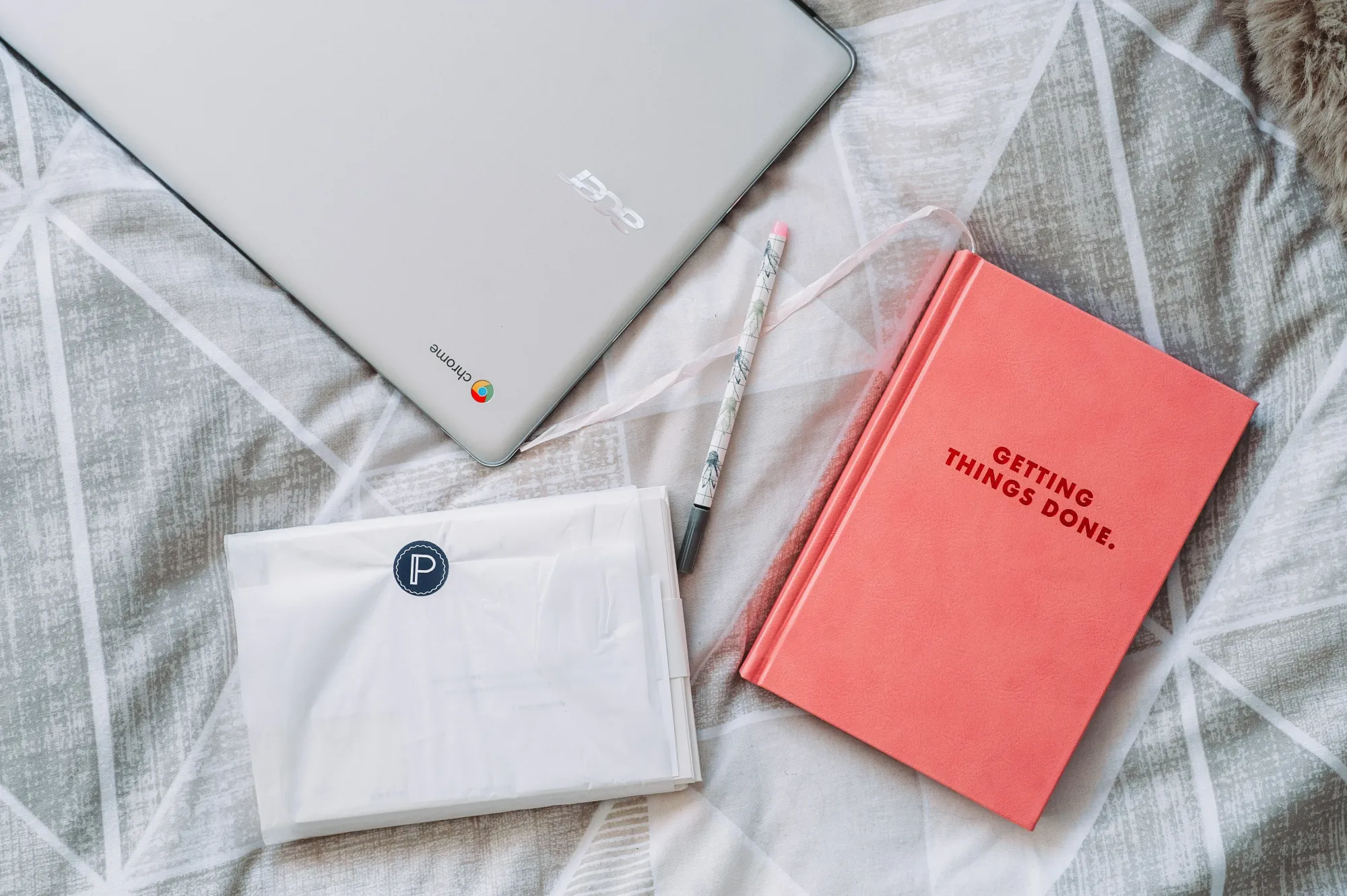 Image of a laptop and notebook on a bed