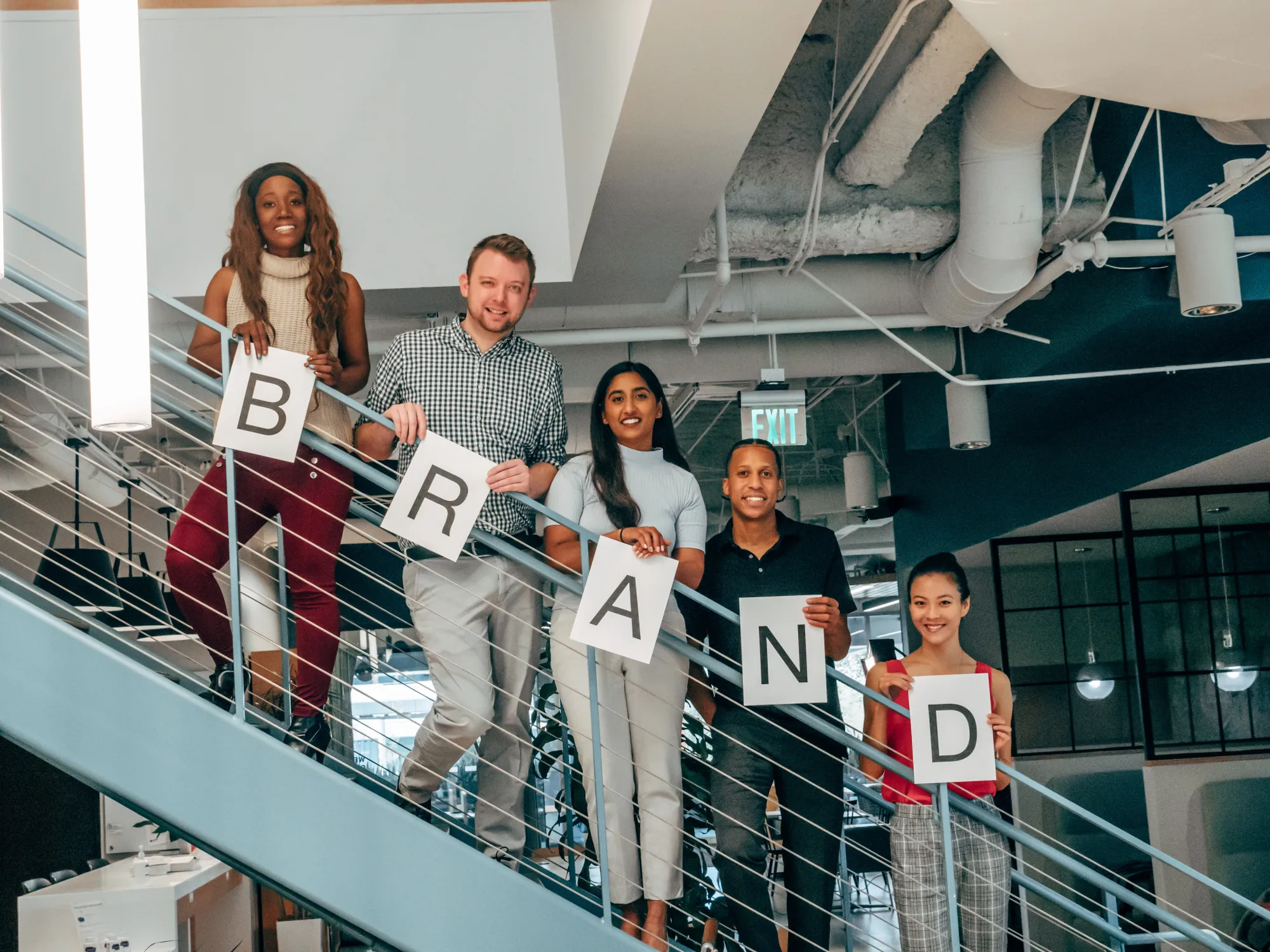 Image of a group of people holding up a sign saying "Brand"