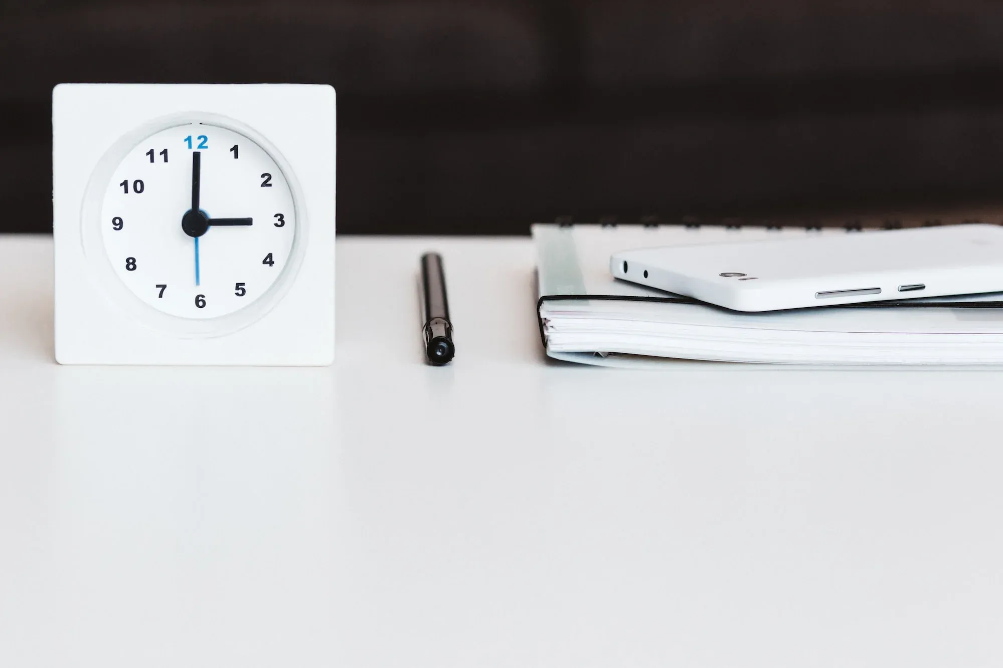 Image of a clock, a pen, and a notebook