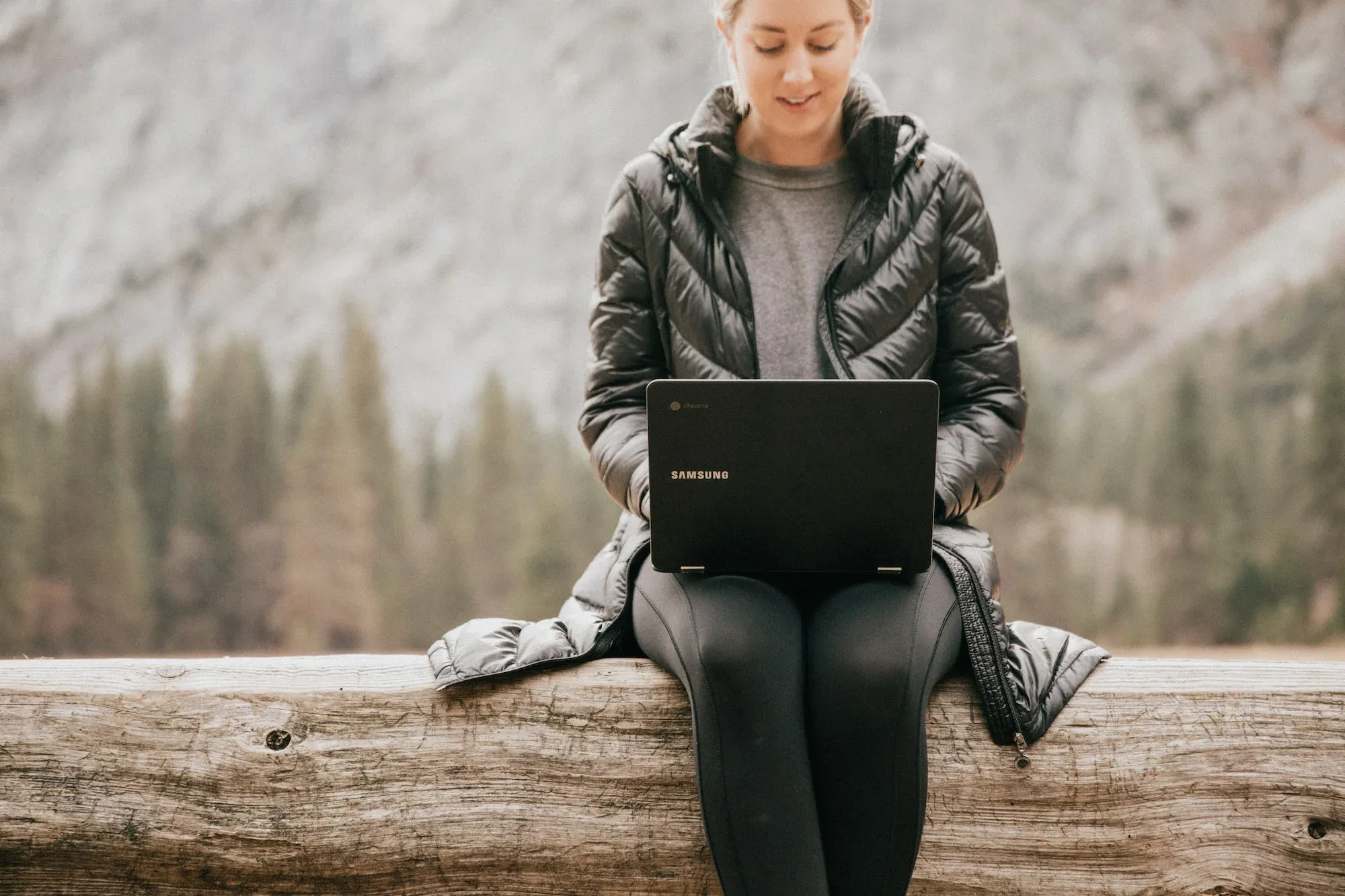 Image of a woman working from her laptop in a mountain setting