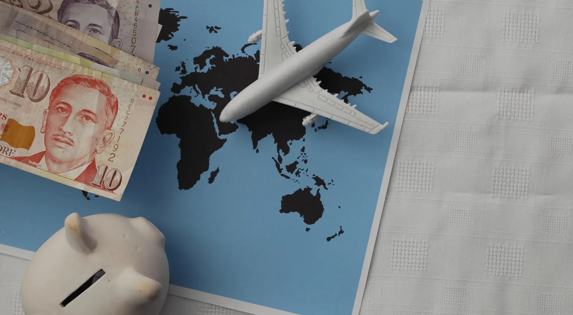 World map with an airplane model and money on top of it