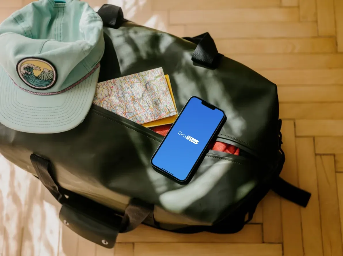 iphone with esim on the screen above a travel bag and next to a cap