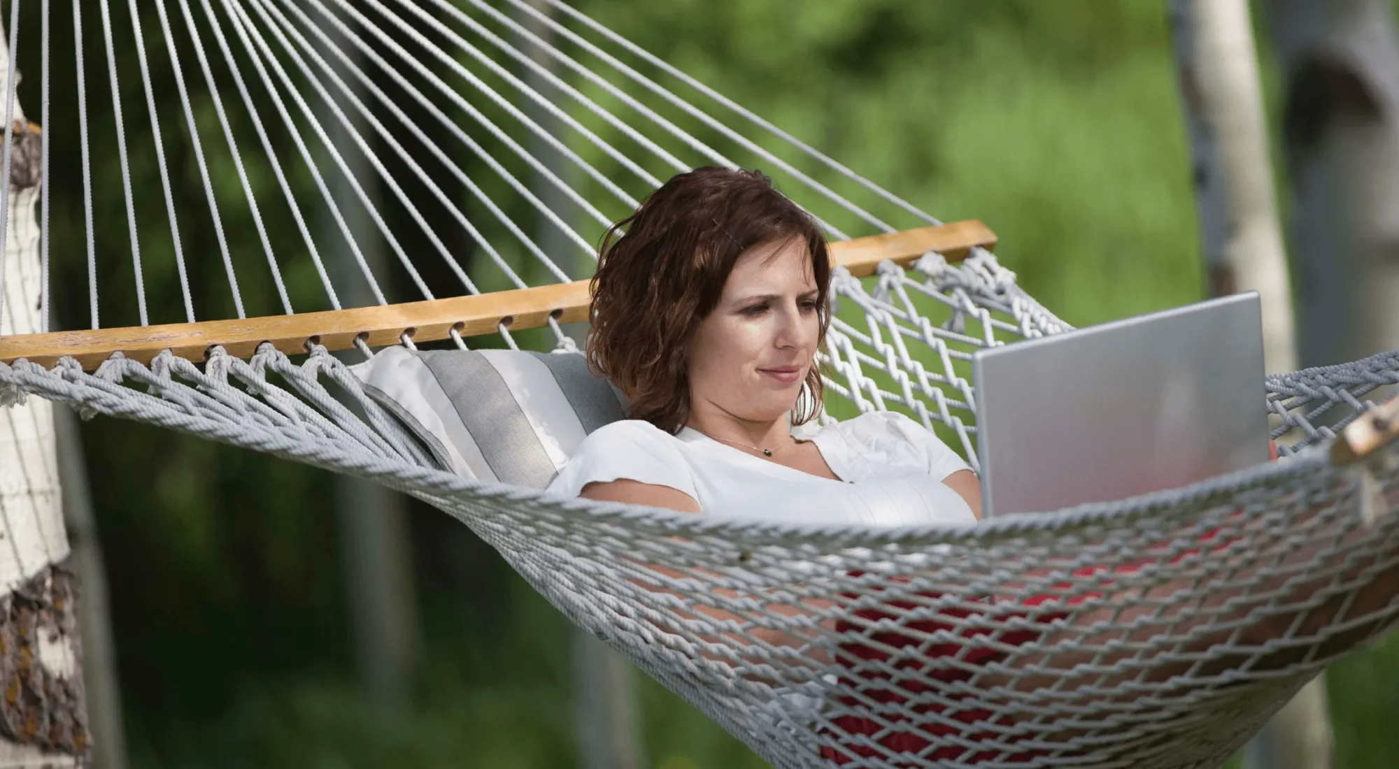 Digital nomad working on her laptop while sitting in a hammock