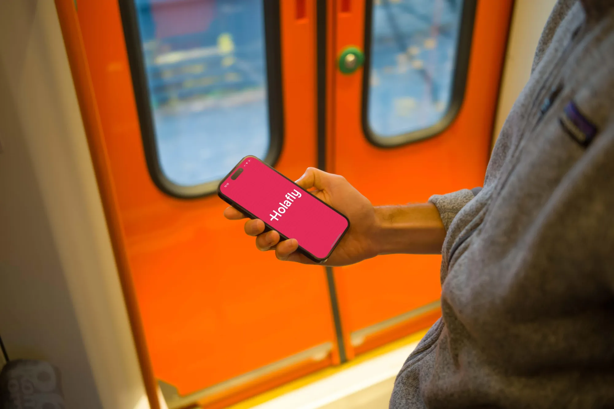 Digital nomad holding a phone with Holafly eSIM app in London tube