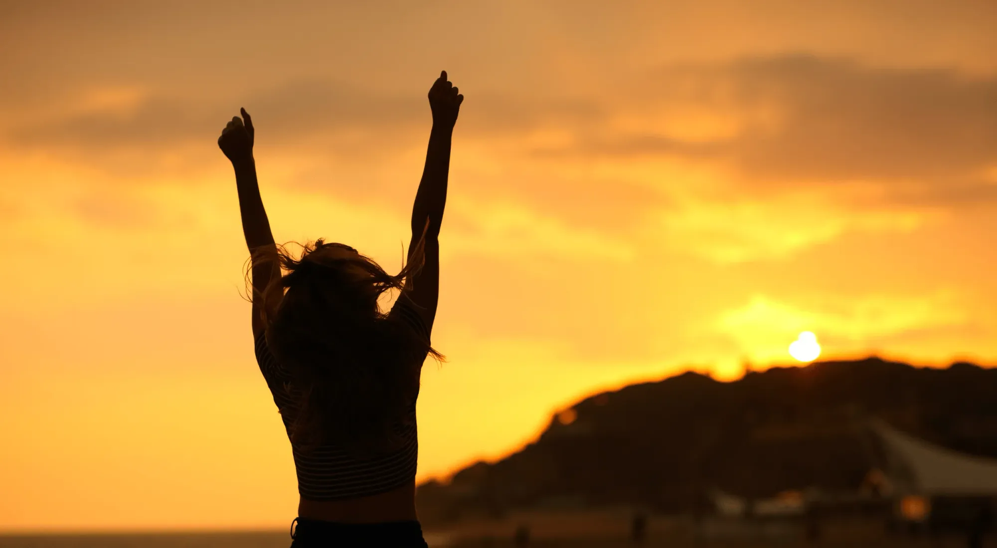 Person celebrating at sunset