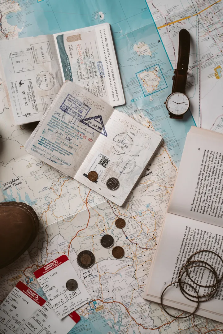Image of a map with money, boarding passes, passport, watch, and book on top of it