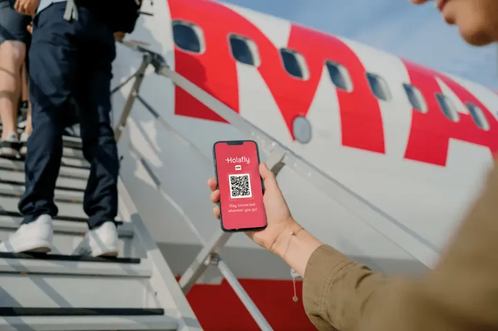 Digital nomad boarding a plane with a smartphone showing an eSIM