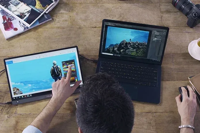 un nomade digitale e lavoratore da remoto che usa un secondo schermo portatile per il suo notebook