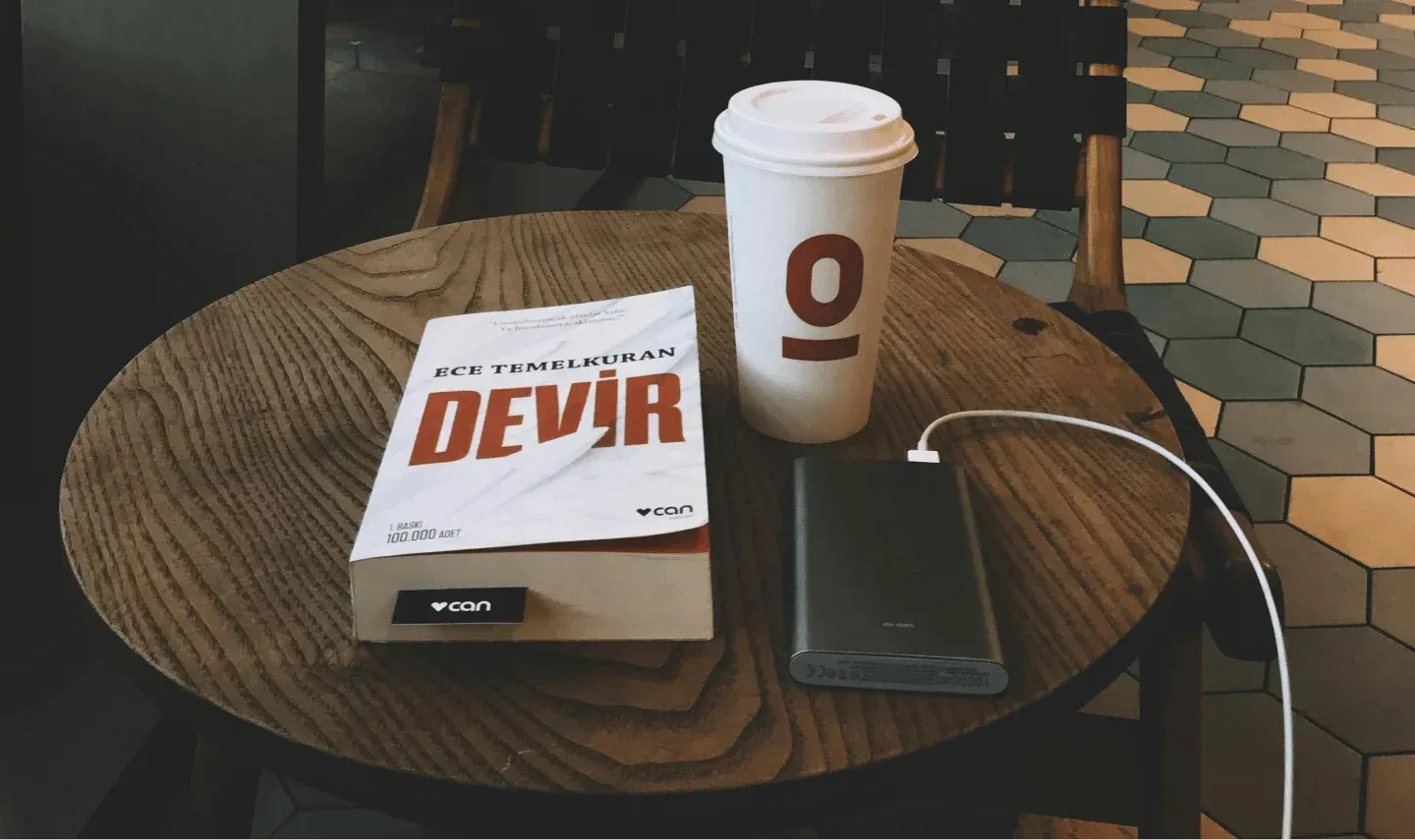 power bank per portatili su un tavolino, accanto ad un libro e una tazza di caffè