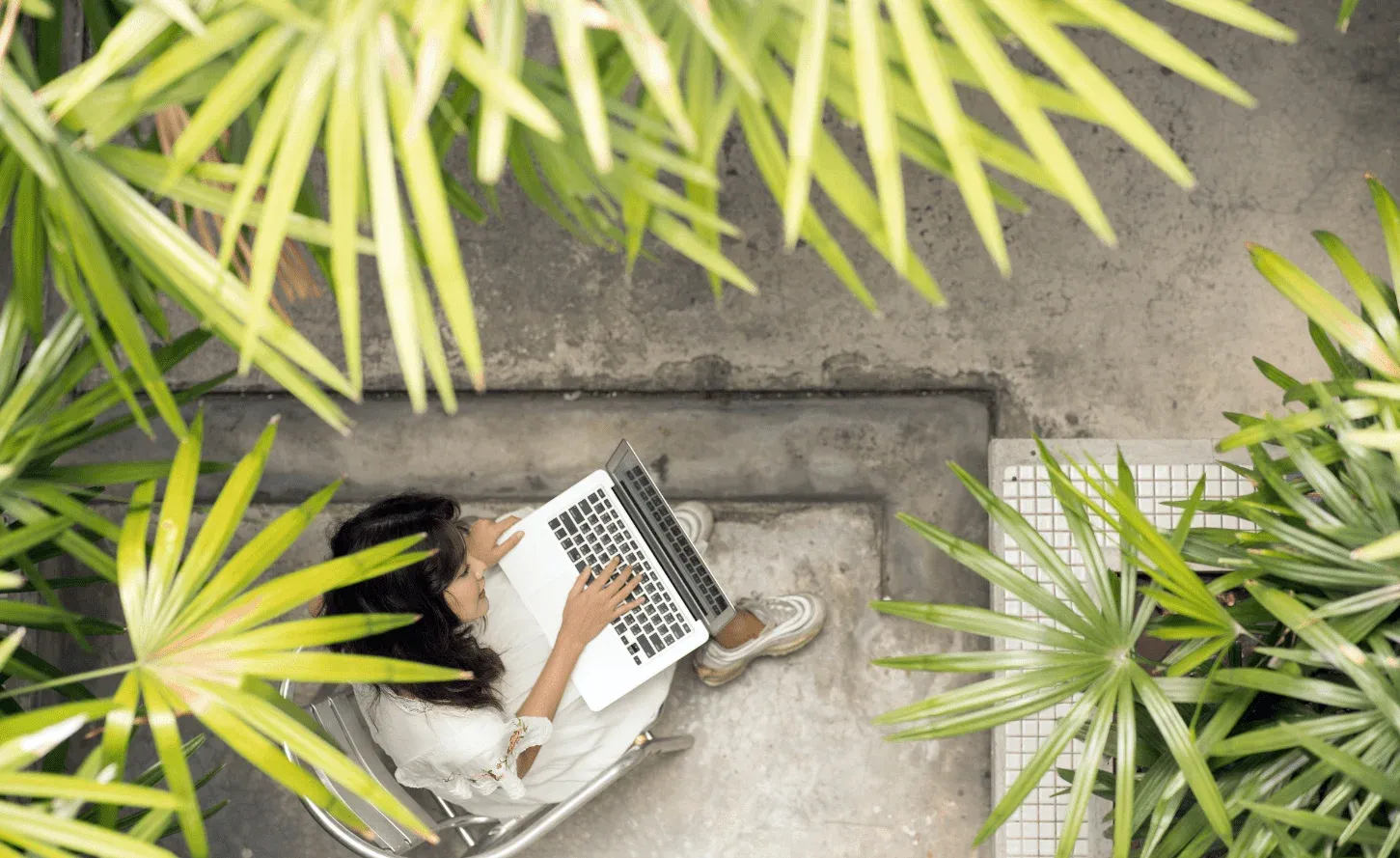 Lavoratrice donna con computer in un giardino tropicale