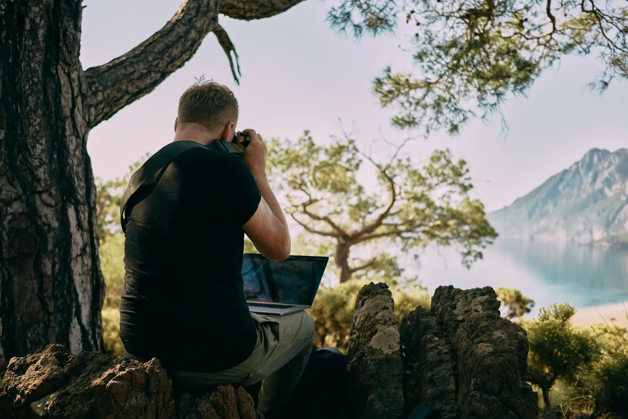 un nomade digitale italiano con il suo portatile, che fotografa un panorama per il suo blog personale