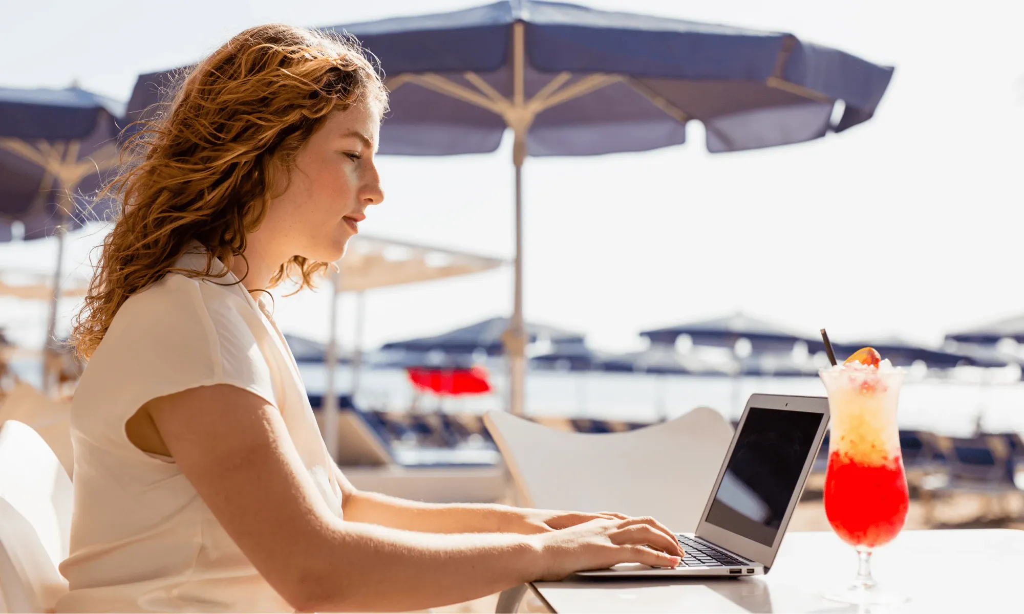 Lavoratrice da remoto lavora con il suo computer dalla spiaggia