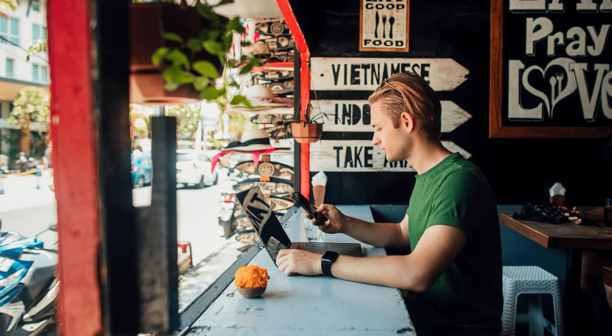 Nomade digitale che lavora col proprio computer in un bar